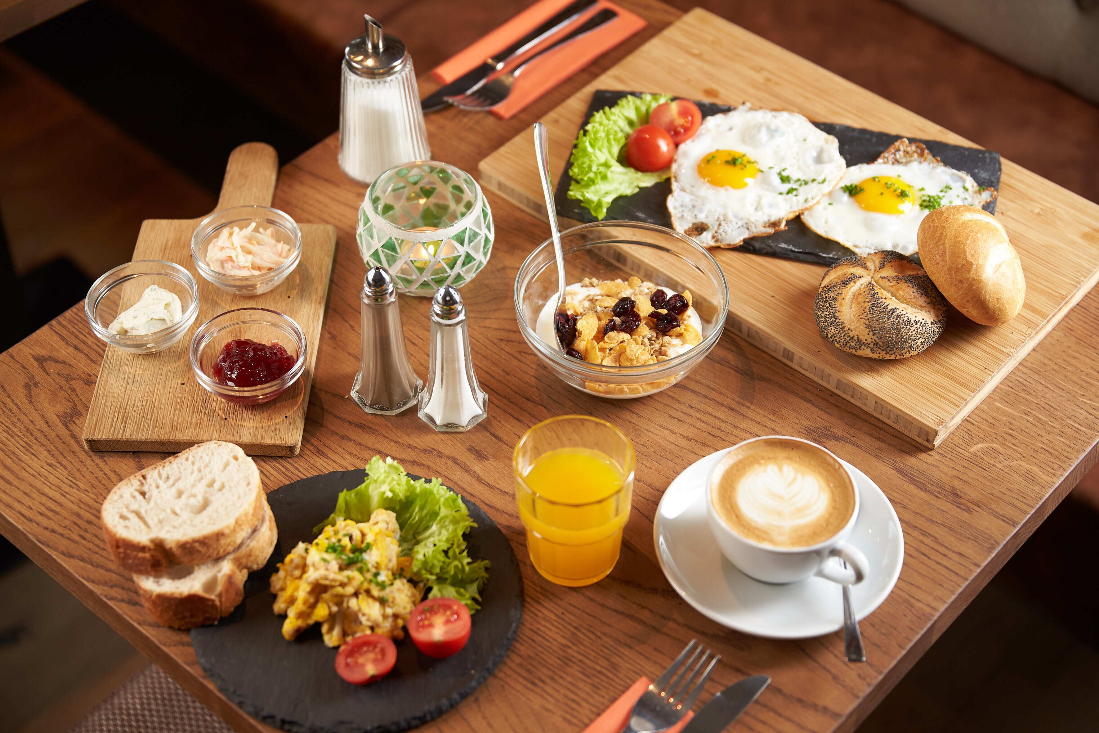 A breakfast table with scrambled eggs, toast, a glass of orange juice, and a cup of coffee.