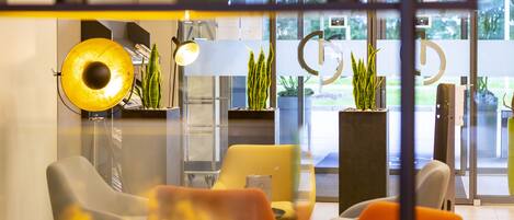 A modern interior with a seating area, a yellow lamp, and potted plants.