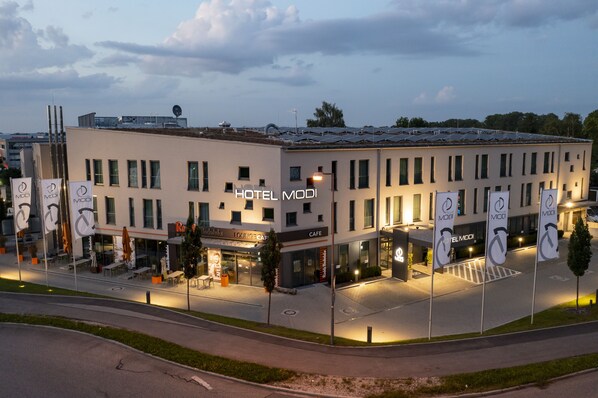 A hotel with a modern facade, multiple dining areas, and a well-lit entrance.
