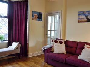 A living room with a purple sofa, a bench, and a door with glass panels.
