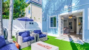 A modern outdoor living area with wicker furniture and a white coffee table, a blue building labeled "CASA AZUL," and a view into the interior. - Beautiful Apartment 5 minutes from the ocean (San Diego)