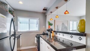 A modern kitchen with a central island, stainless steel appliances, and pendant lighting. - Beautiful Apartment 5 minutes from the ocean (San Diego)