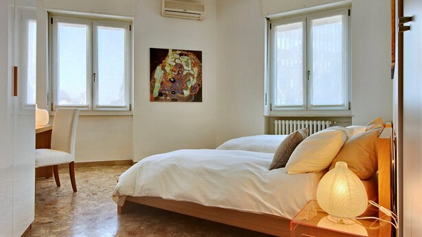 A bedroom with a bed, a chair, a desk, and a painting on the wall.