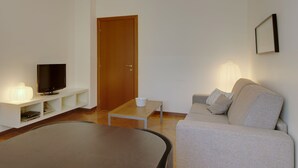A living room with a television, a coffee table, a sofa, and a door.
