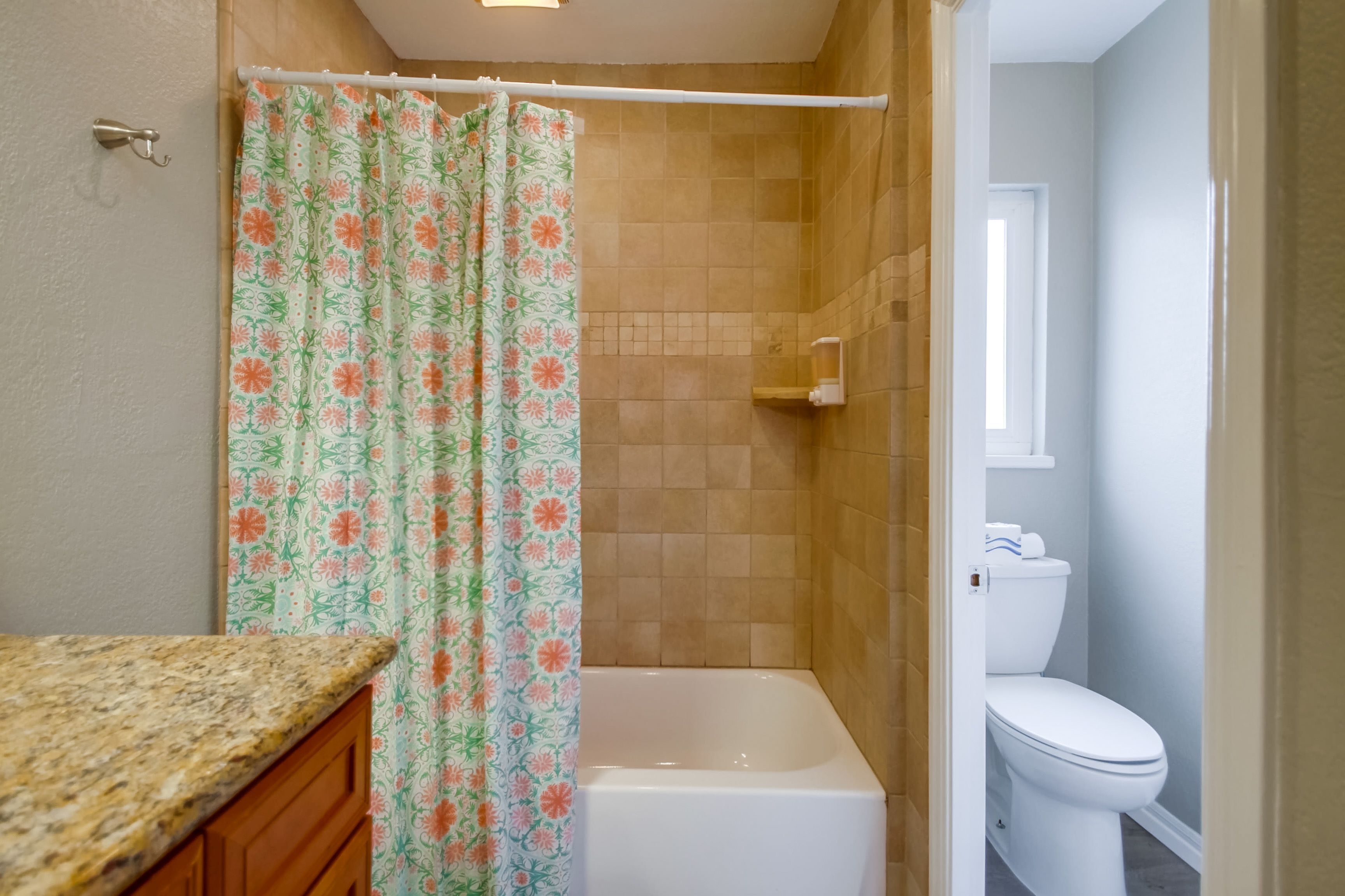 Un baño con ducha, inodoro y encimera de granito.