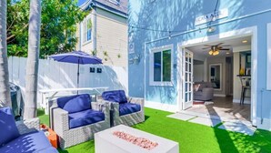 A modern outdoor living area with a white coffee table, blue cushioned seating, and a patio umbrella. - Beautiful Apartment 5 minutes from the ocean (San Diego)