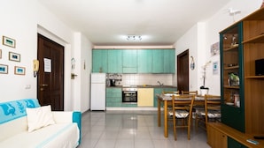 Un espacio habitable compacto con kitchenette, comedor y sofá.
