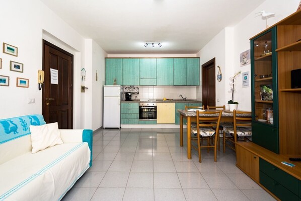 Un espacio habitable compacto con kitchenette, comedor y sofá.
