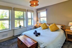 A bedroom with a bed, bedside tables, a bench, and large windows.
