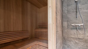 Una sauna amb bancs de fusta i una zona de dutxes amb rajoles de pedra.