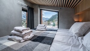 Un dormitori modern amb un llit gran, vista a les muntanyes i un fanal.