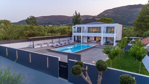 A modern two-story house with a swimming pool, outdoor seating, and a view of the surrounding hills. - The Divine Villa of Zakynthos (Zakynthos (Zante))
