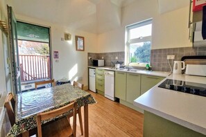 A compact kitchen with a dining table, a microwave, a dishwasher, and a window.