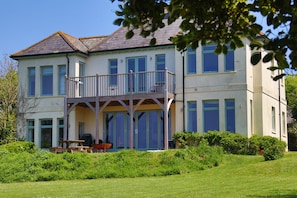 A two-story house with a balcony, a covered porch, and a well-maintained lawn.