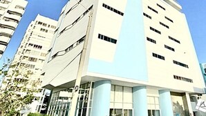 Un edificio alto y moderno con una torre central destacada y varios balcones.