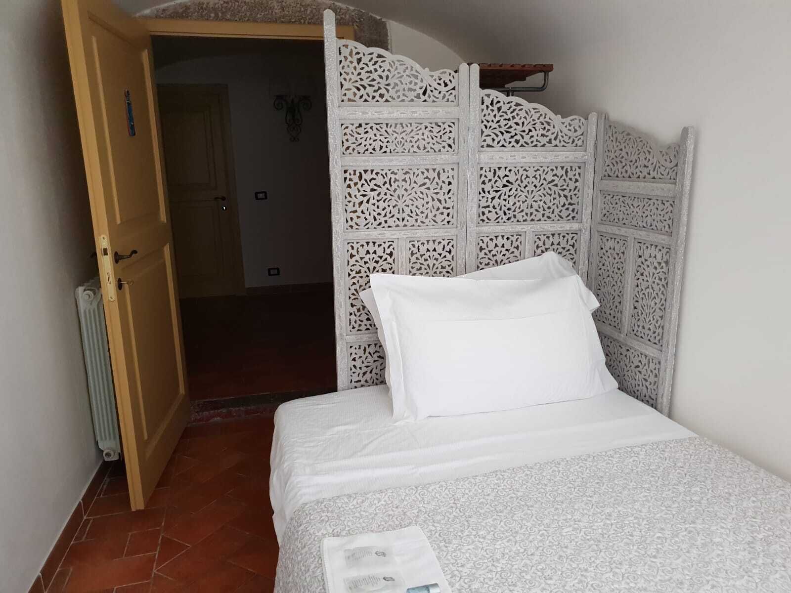 A bedroom with a bed, a white headboard, and a wooden door.