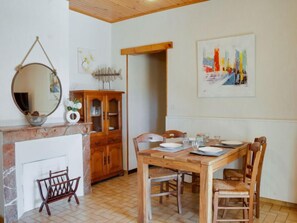 A dining area with a wooden table and chairs, a wooden cabinet, a fireplace, and a framed painting on the wall.
