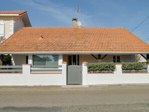 A two-story house with a tiled roof, a satellite dish, and a gated entrance.