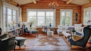 Un intérieur chaleureux de chalet en bois avec une cheminée, de grandes fenêtres et un décor rustique.