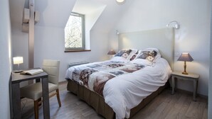 A bedroom with a large bed, two bedside lamps, a small table with a chair, and a window with a view of trees. - Gite La Borie Haven of peace in the Perigord (Cénac-et-Saint-Julien)
