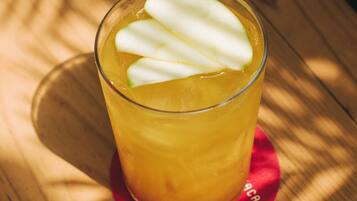 Un vaso de jugo de naranja con rebanadas de manzana sobre una mesa de madera.