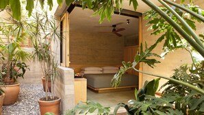Een slaapkamer met een bed, een plafondventilator en potplanten.