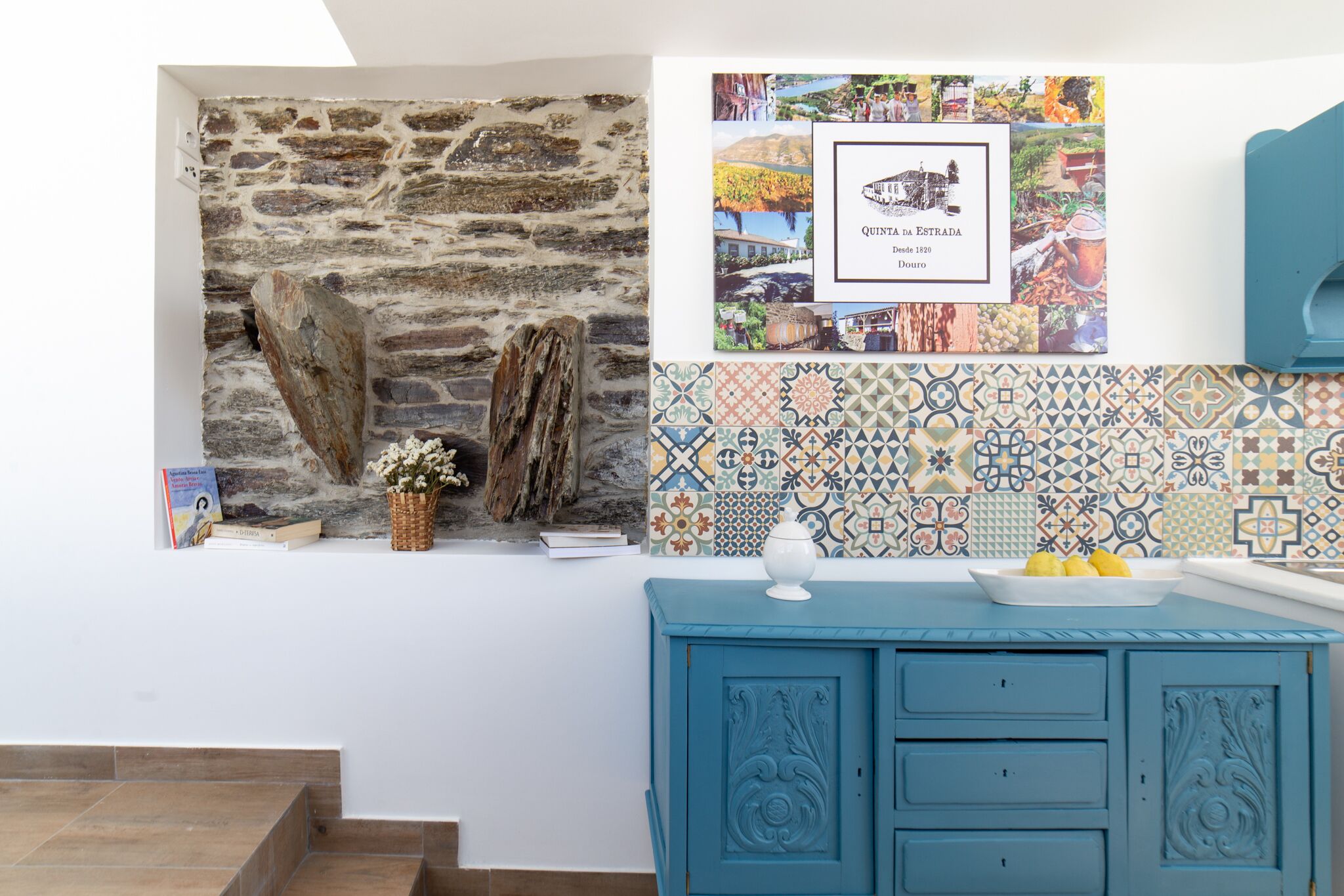 A kitchen with a stone wall, a tiled backsplash, and a blue cabinet.