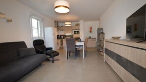 A modern living room with a grey sofa, a black chair, and a dining area with a table and chairs. - Cozy apartment in Moriani Plage (Moriani Plage)