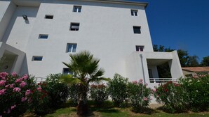 A modern multi-story building with a flat facade, multiple windows, and a central entrance. - Cozy apartment in Moriani Plage (Moriani Plage)