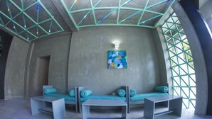 A modern interior with a curved seating area, a painting on the wall, and a geometric ceiling design. - Somerset Mirissa Beach (Mirissa)