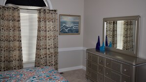 A bedroom with a bed, a dresser, a mirror, and a painting on the wall. -  Charming Country Home — 1,400+ Sq Ft, Minutes from ECU Health (Winterville)