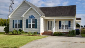 A single-story house with a gabled roof, a front porch, and a small front yard. -  Charming Country Home — 1,400+ Sq Ft, Minutes from ECU Health (Winterville)