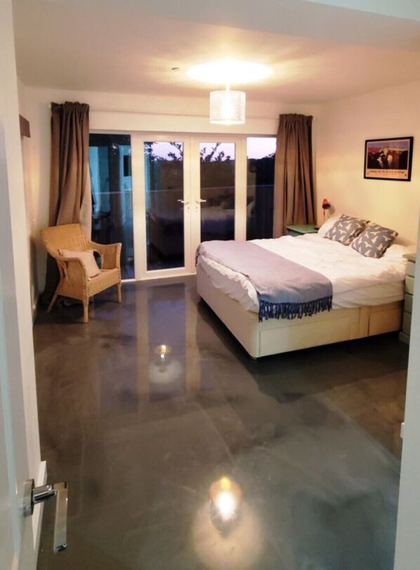 A bedroom with a bed, a chair, and a sliding glass door leading to a balcony.