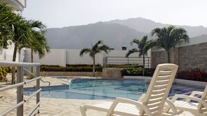 A pool area with lounge chairs, a stone tiled deck, and a view of mountains in the background. - Apartamento de Yuly Cerca a la Playa Sector Bello Horizonte Santa Marta  (Santa Marta)