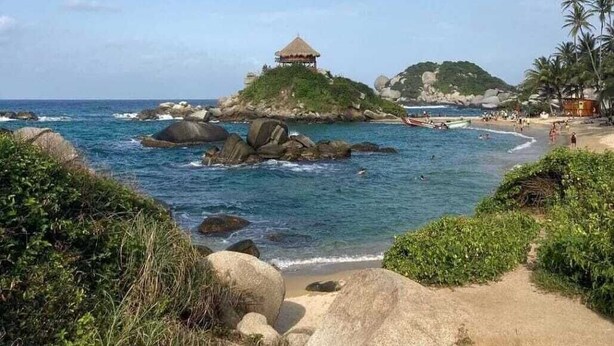 A beach with a gazebo on a small island, surrounded by rocks and palm trees. - Apartamento de Yuly Cerca a la Playa Sector Bello Horizonte Santa Marta  (Santa Marta)