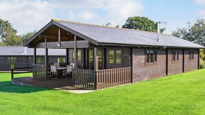 A wooden building with a covered patio and a grassy lawn. - 3 bedroom accommodation in Nomansland, near Tiverton (Nomansland, near Tiverton)