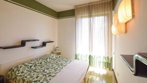 Un dormitorio con cama, mesitas de noche, un espejo y una ventana con cortinas.