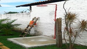 A concrete water feature with a red pipe, a ladder, and a small tree in a garden area. - Chale near the best clubs, downtown, restaurants and venue. (Caldas Novas)