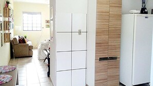 A compact kitchen with a white refrigerator, a wooden cabinet, and a dining area with a table and chairs. - Chale near the best clubs, downtown, restaurants and venue. (Caldas Novas)