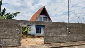 A house with a red roof, a small front porch, and a stone wall in the foreground. - Chale near the best clubs, downtown, restaurants and venue. (Caldas Novas)