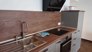 Une cuisine moderne dotée d’un évier en acier inoxydable, d’un four encastré et d’un plan de travail en bois.
