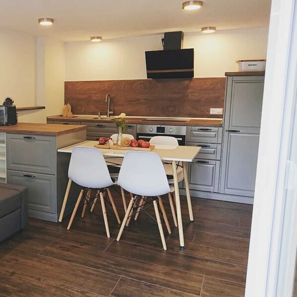 A modern kitchen with a dining area, wooden cabinets, and a built-in oven.