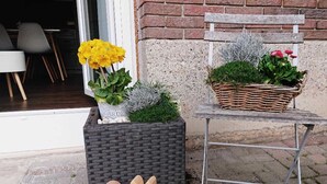 Un espace jardin agrémenté d’un jardinière en osier, d’une sculpture en bois représentant un lapin et d’un panier en osier rempli de fleurs.