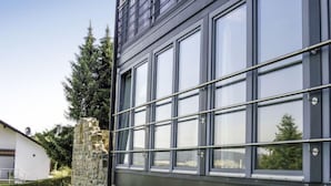 A modern building with large windows and a stone wall.