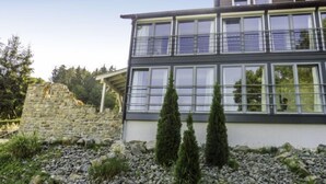 A modern two-story building with large windows and a stone wall.
