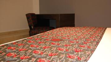 Una habitación de hotel con una cama cubierta por una colcha estampada con motivos florales, una silla y una chimenea.