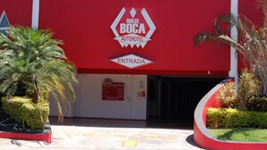 La entrada a Dulce Boca AutoHotel, con fachada roja, palmeras y un letrero que indica la entrada.
