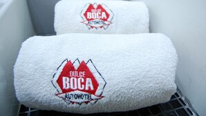 Dos toallas blancas con logotipos bordados sobre un perchero de metal.