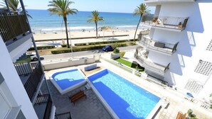 Edificio residencial con piscina en la azotea y vistas a la playa, bajo un cielo despejado.