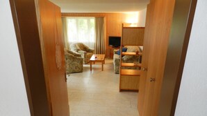 A hotel room with a wooden door, a sofa, a coffee table, and a TV. - Diamant by Interhome (Zweisimmen)